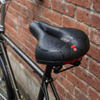 Ergonomic bicycle saddle with padding and reflector strips